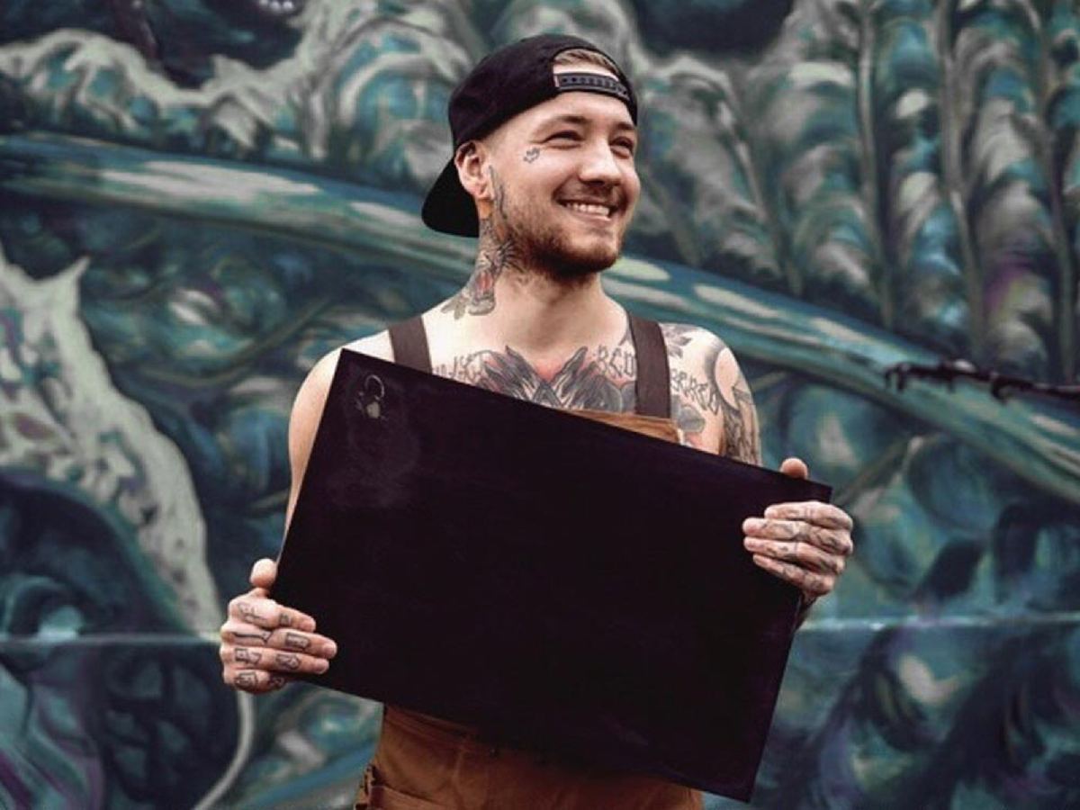 Porträt von Benni Radtke, lächelnd, mit sichtbaren Tattoos an Armen und Brust