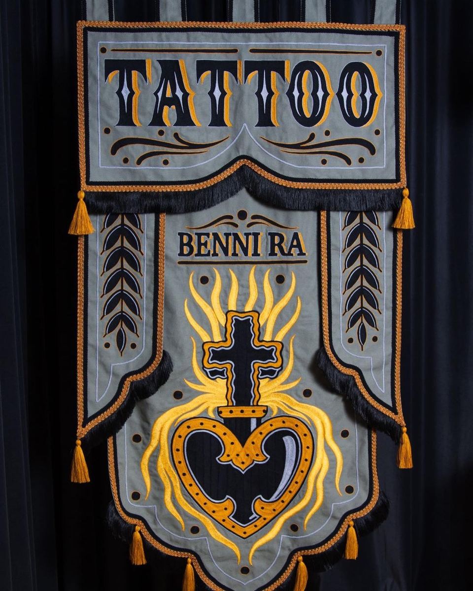 Studio-Banner mit Schriftzug „Tattoo Benni Ra“ und traditionellem Herz-Motiv