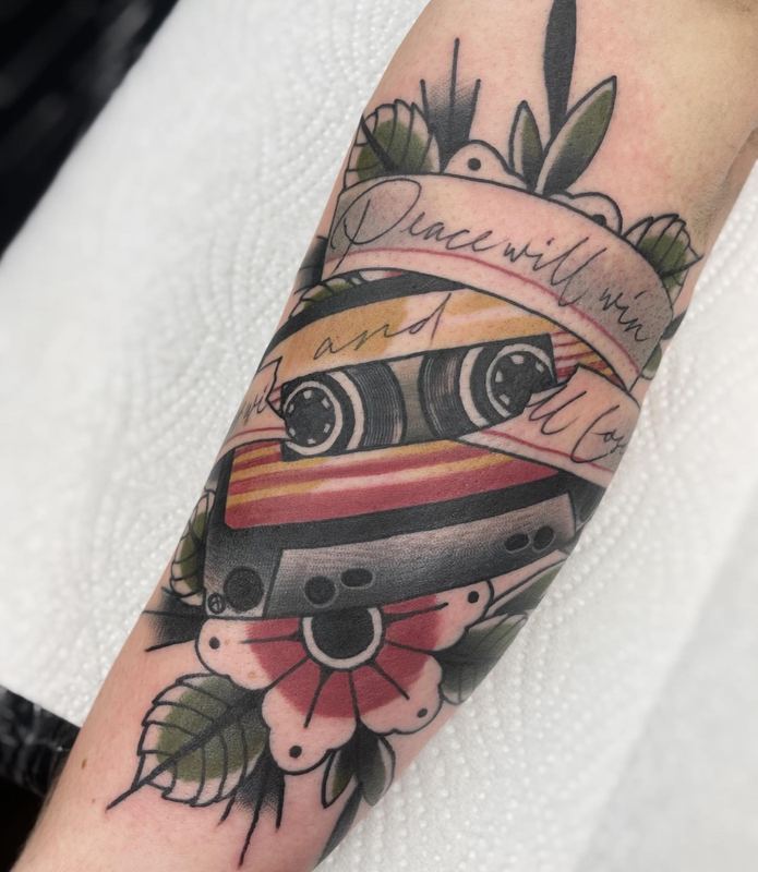 Kassetten-Tattoo mit Schriftzug „Peace will win“ und Blumen