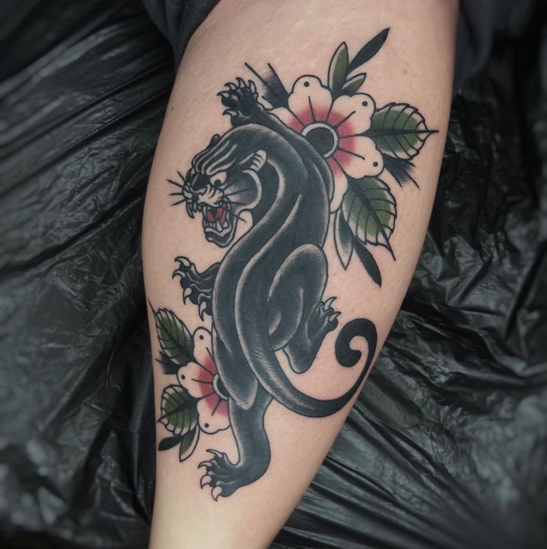 Traditional Panther-Tattoo mit Blütenzweig am Unterarm